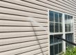 Power washing. House wall vinyl siding cleaning with high pressure water jet.